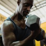 mature man exercising with weights in gym building muscle after 50