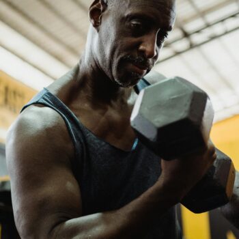 mature man exercising with weights in gym building muscle after 50