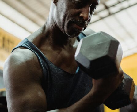 mature man exercising with weights in gym building muscle after 50