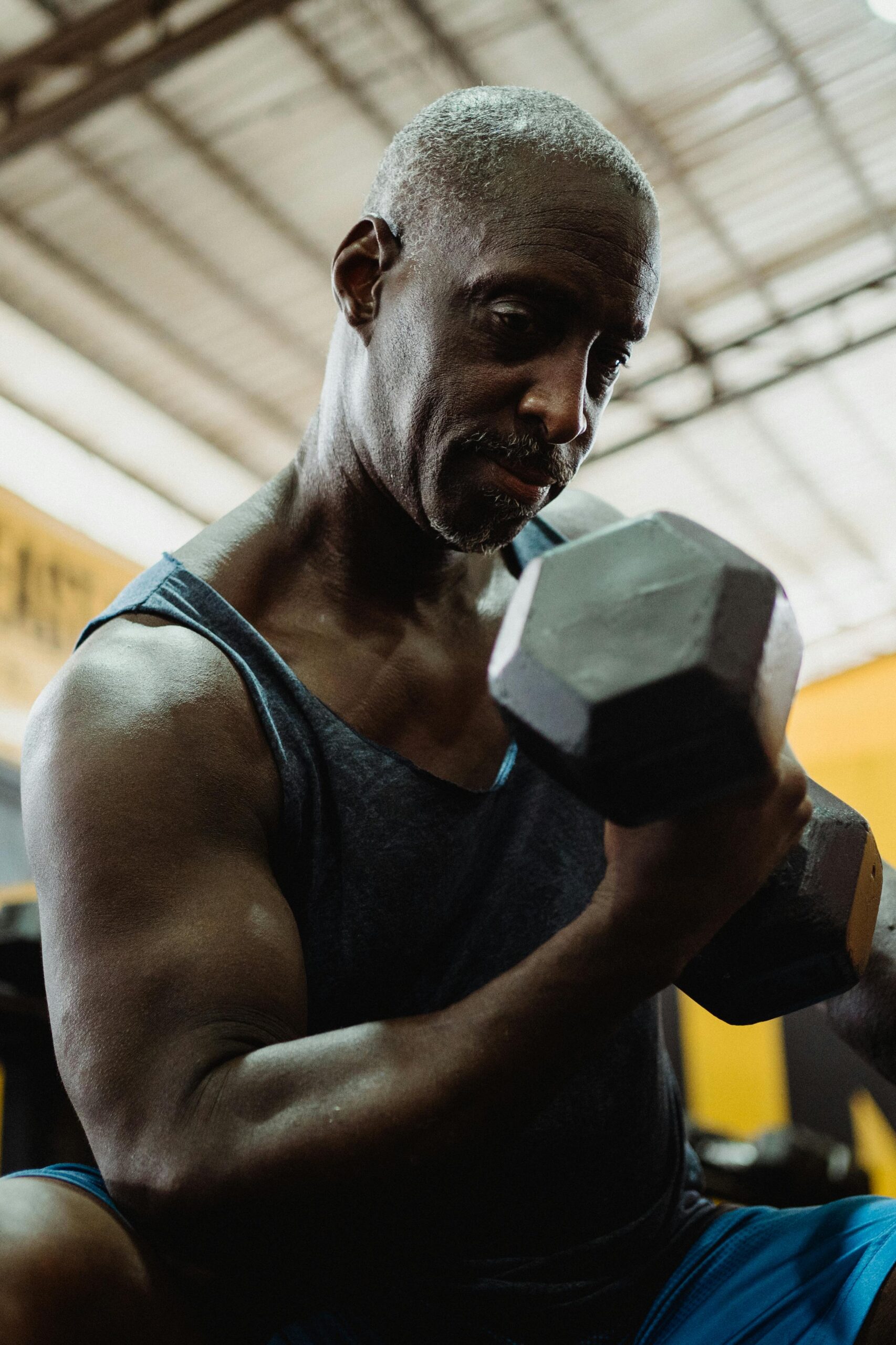 mature man exercising with weights in gym building muscle after 50