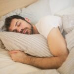 Person sleeping with clock showing optimal sleep duration to prevent brain and organ aging