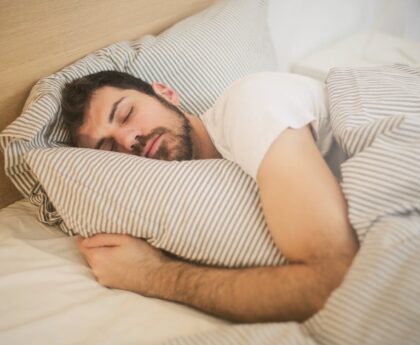 Person sleeping with clock showing optimal sleep duration to prevent brain and organ aging