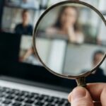 A magnifying glass held over a laptop video call screen