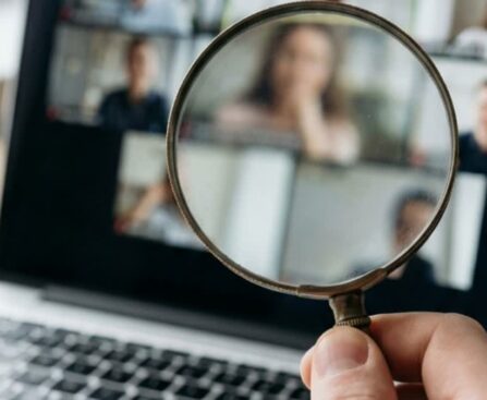 A magnifying glass held over a laptop video call screen