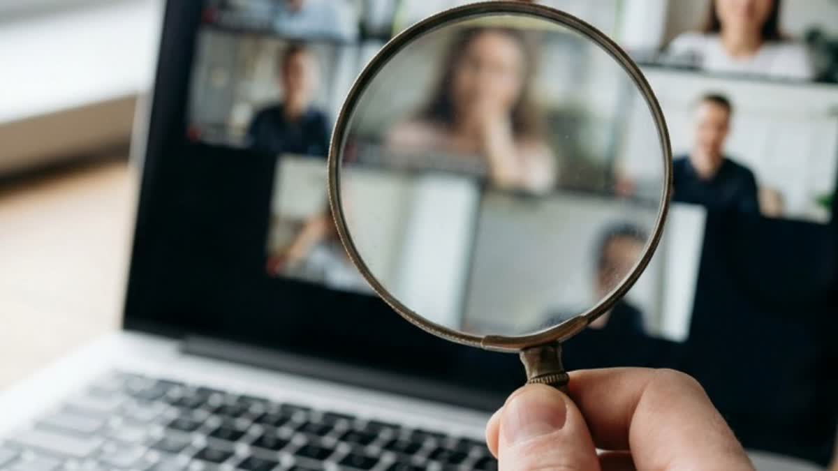 A magnifying glass held over a laptop video call screen