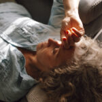Woman resting on a couch with her hand on her forehead, expressing stress